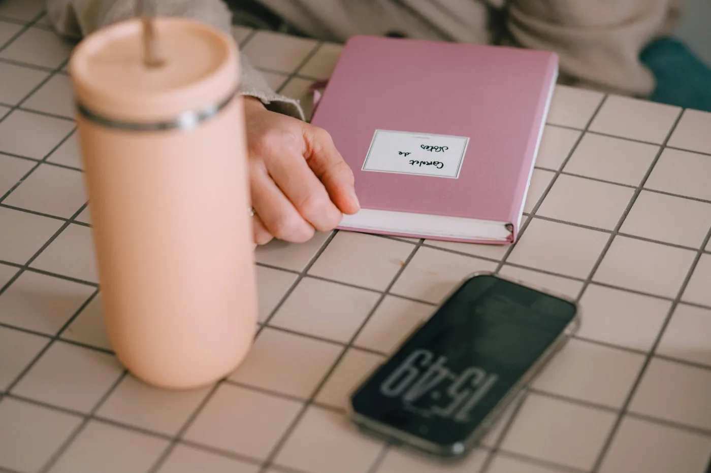Pink tumbler beside a notebook and smartphone